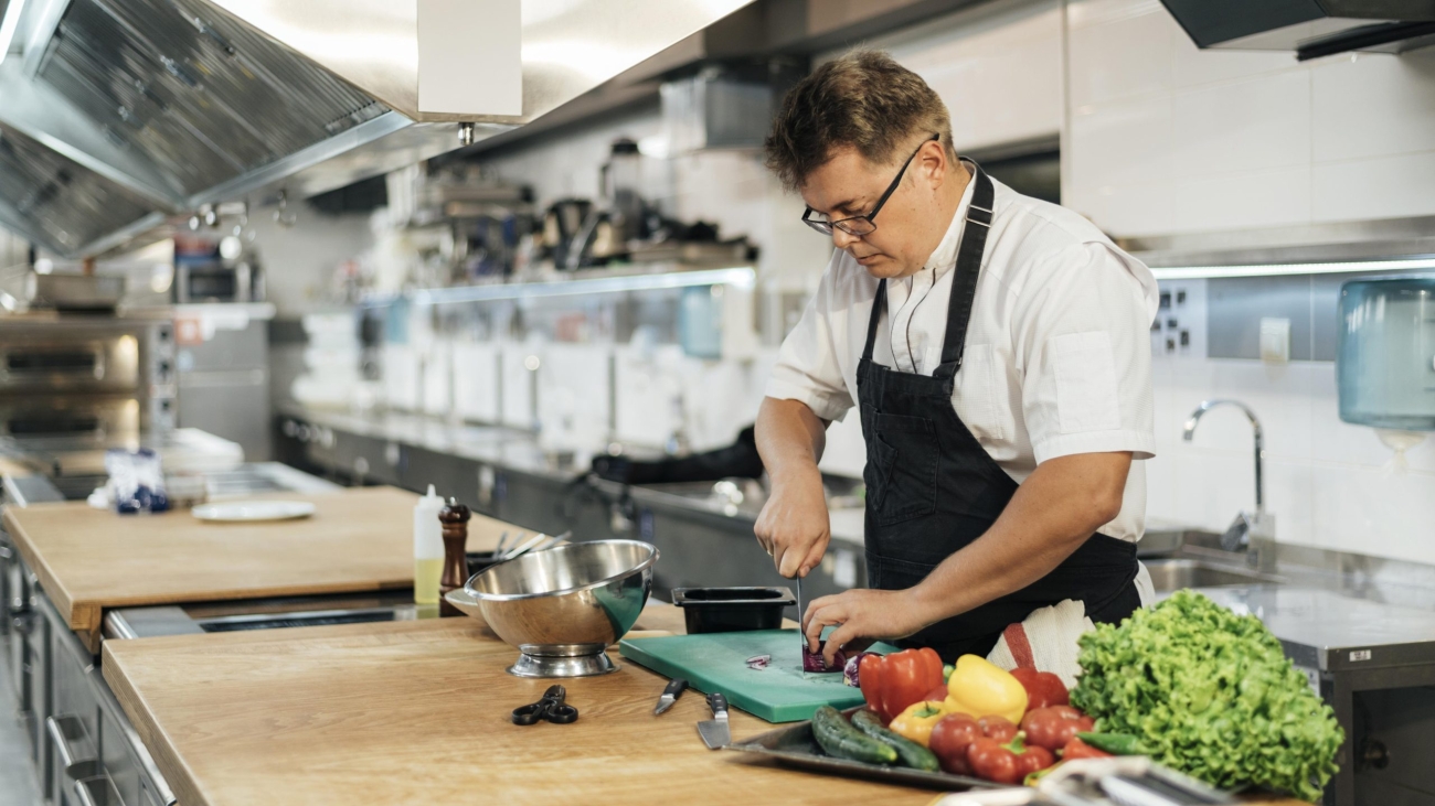 male-chef-with-apron-chopping-vegetables