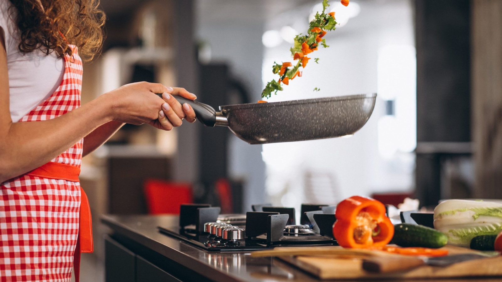 Woman chef cooking vegetables in pan